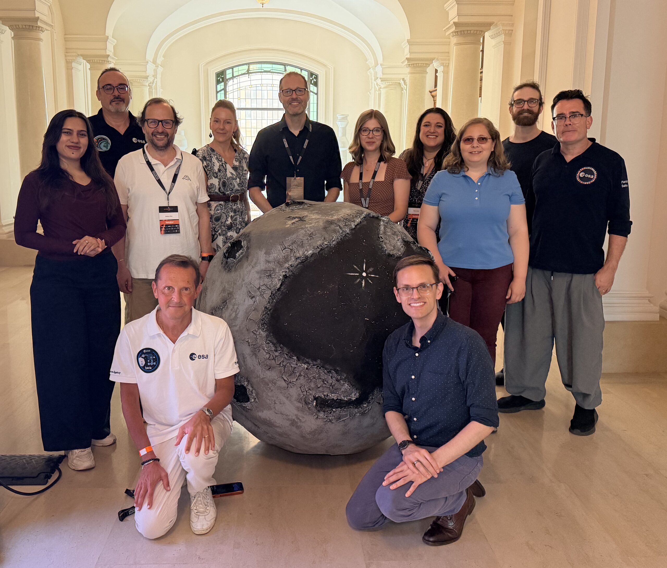 Several people standing around a model of an asteorid